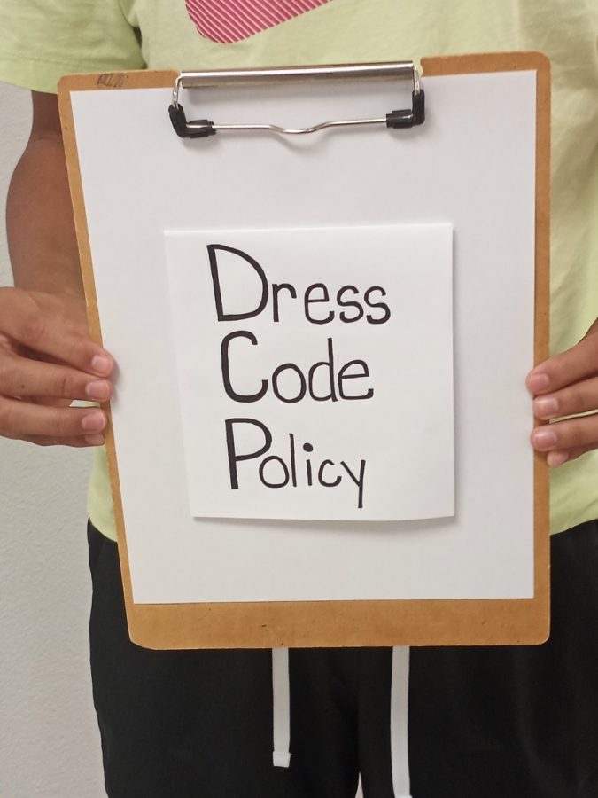 Alex Alvarez holding dress code sign