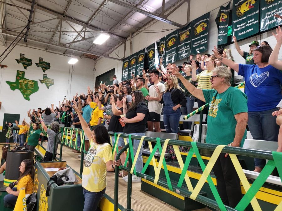 Previous and current students, parents, teachers, staff members, and community members raising their Wolverine paw as the school song was played during the pep rally.