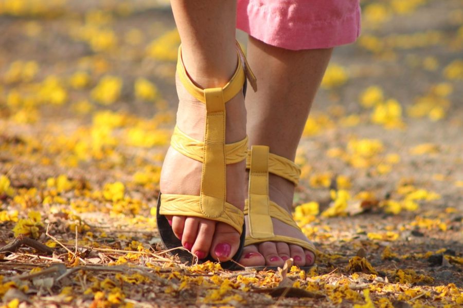 Woman+walking+through+environmental+vegetation+in+yellow+sandals.